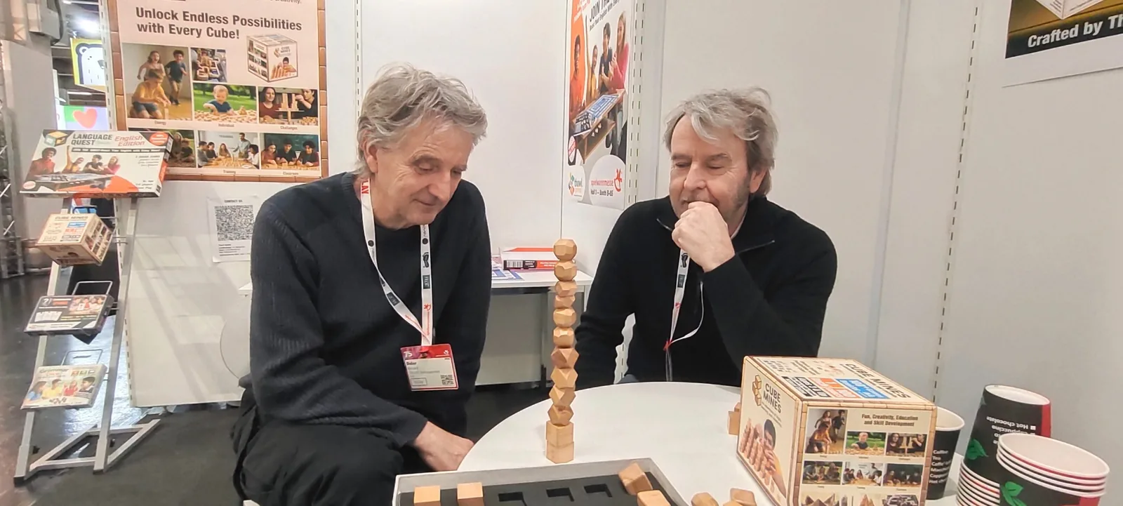Two trade visitors from France exploring a wooden construction activity at the Thowl Games booth