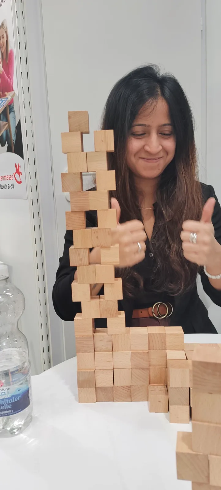 Indian student based in Germany smiling beside a tall wooden Cube Mines structure