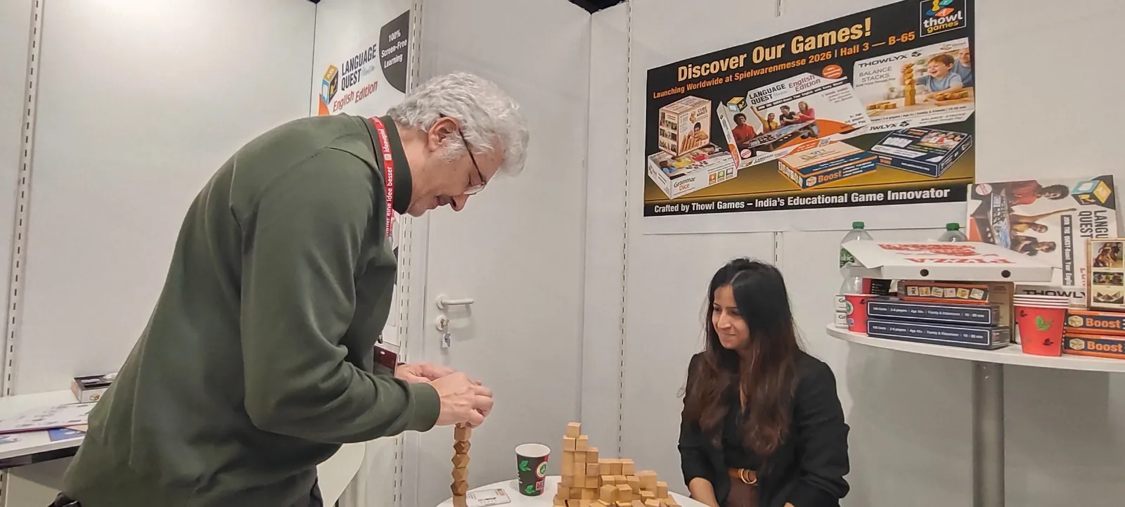 Two visitors exploring a wooden construction game at the Thowl Games booth